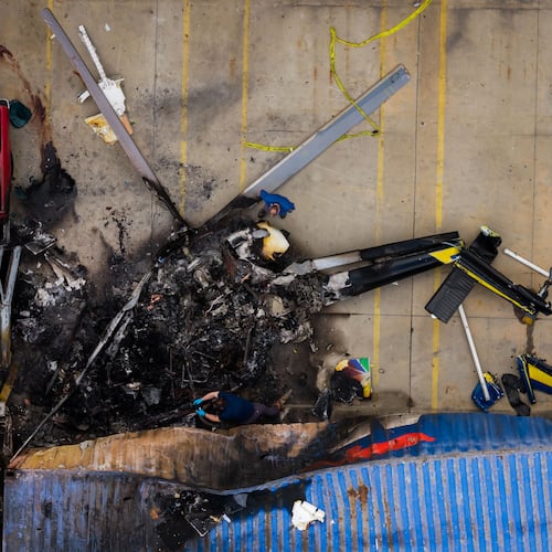 In this aerial view, people investigate the aftermath of a news helicopter crash in Chatsworth, a neighborhood in Los Angeles, on Wednesday, Sept. 16, 2026.(AP Photo/Ethan Swope)