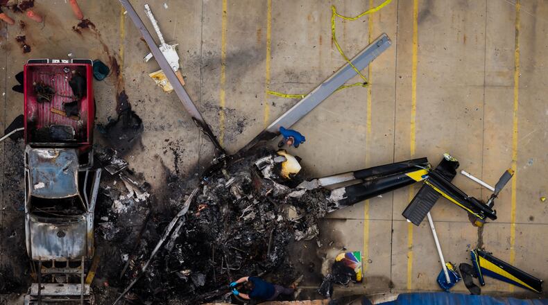 In this aerial view, people investigate the aftermath of a news helicopter crash in Chatsworth, a neighborhood in Los Angeles, on Wednesday, Sept. 16, 2026.(AP Photo/Ethan Swope)