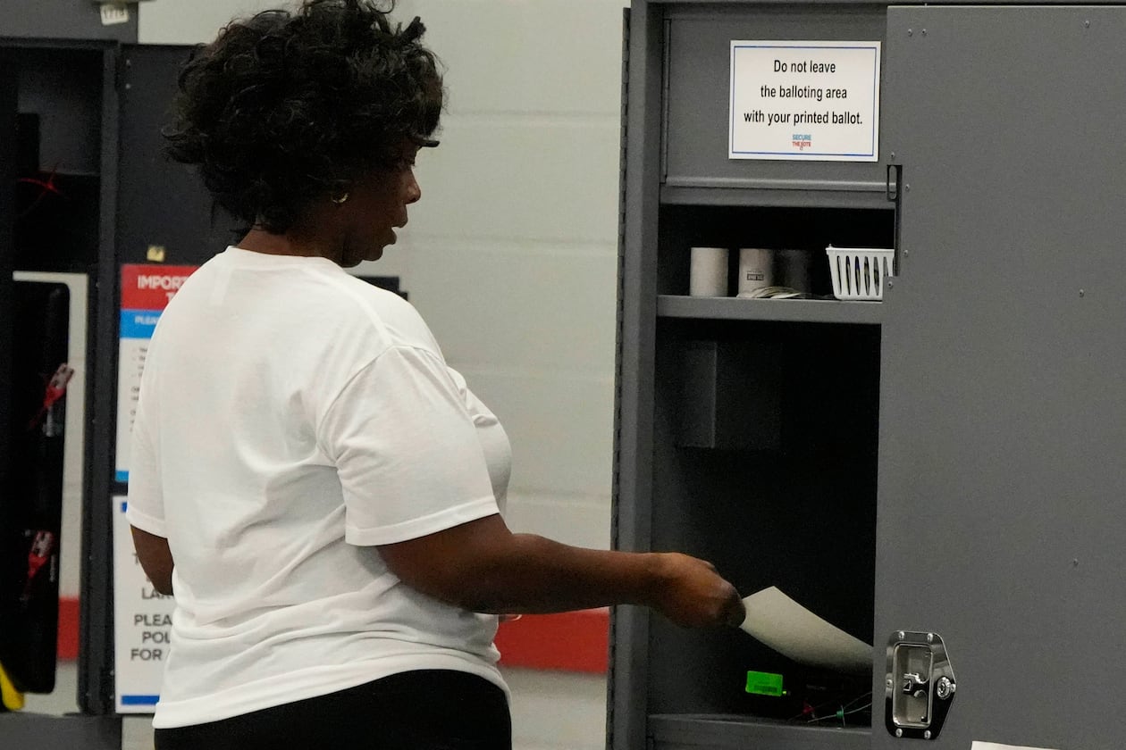 A woman places her paper ballot into a machine after voting in a runoff election at the C.T. Martin Recreation Center last month in Atlanta. (Mike Stewart/AP)