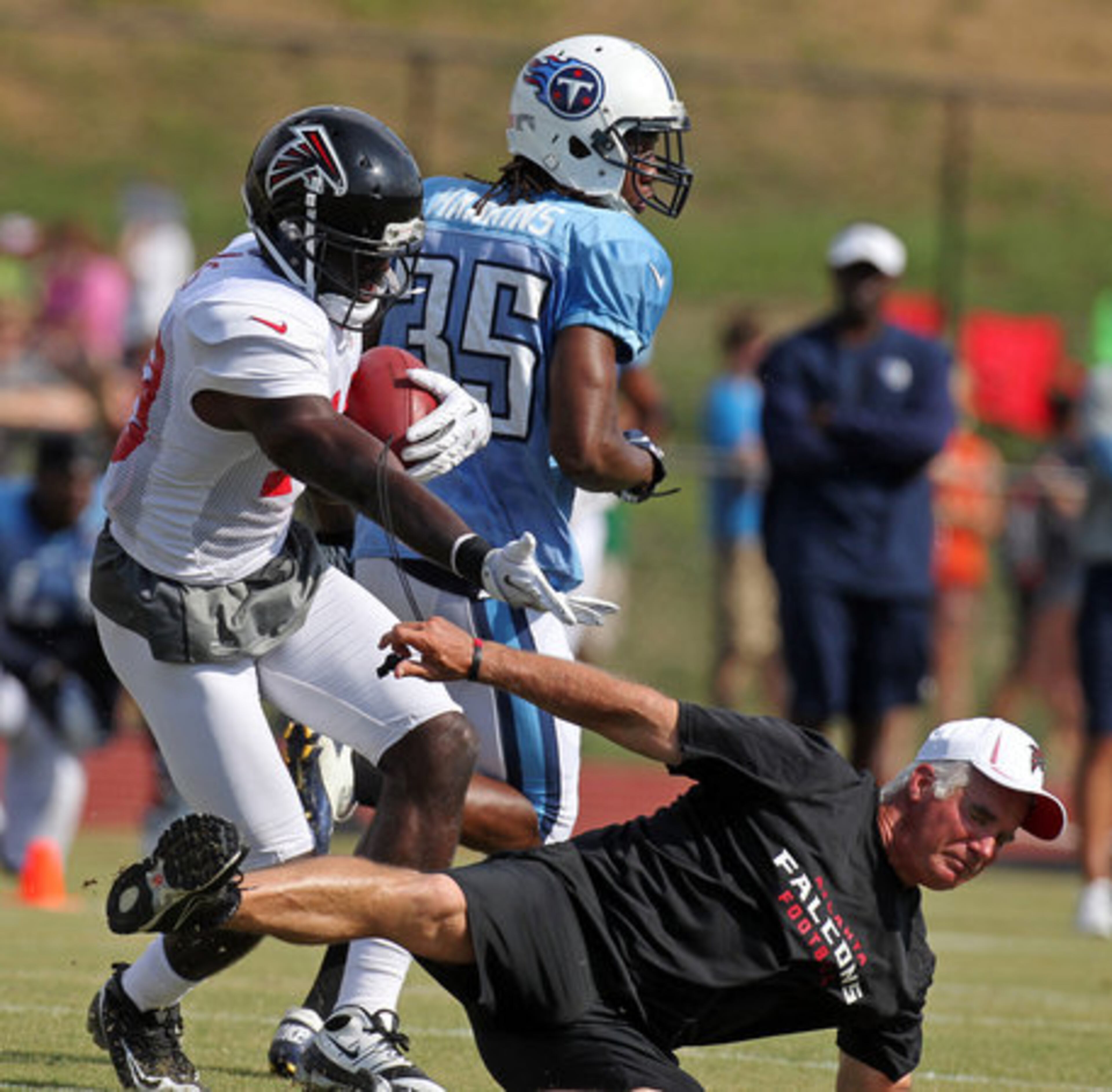 Atlanta Falcons wide receiver Drew Davis, left, reaches out after colliding with head coach Mike Smith following a catch against Tennessee Titans cornerback Chris Hawkins (35) during a joint NFL football practice in Dalton, 2012. (AJC)