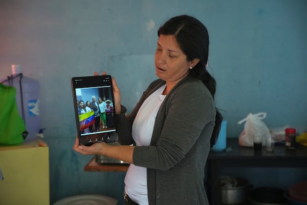 FILE - Venezuelan Betania Rodriguez holds up her tablet to show a group photo taken with Pope Leo XIV, then Bishop Robert Prevost, at a migrant shelter run by Prevost and the Order of St. Vincent de Paul, in Chiclayo, Peru, Saturday, May 10, 2025. (AP Photo/Guadalupe Pardo, File)