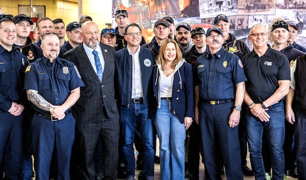 Pennsylvania Gov. Josh Shapiro and first lady Lori Shapiro, in center, pose for a photo with firefighters, Thursday, April 17, 2025, thanking them for their efforts after Sunday's arson attack at the Governor's Residence. (Dan Gleiter/The Patriot-News via AP)