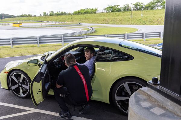 Zachary Hansen gets advice from instructor Marc Piscitelli before going for a test drive in a Porsche 911 at the Porsche Experience Center. (Arvin Temkar/AJC)