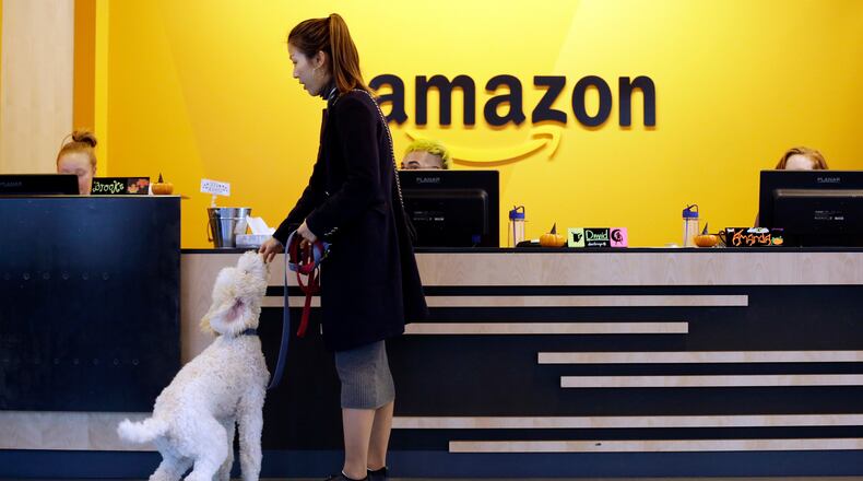 In this Wednesday, Oct. 11, 2017, photo, an Amazon employee gives her dog a biscuit as the pair head into a company building, where dogs are welcome, in Seattle. (AP Photo/Elaine Thompson)