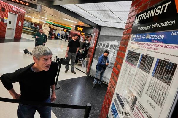 A commuter checks a NJ Transit bus schedule in the Port Authority Bus Terminal, in New York, Friday, May 16, 2025. (AP Photo/Richard Drew)