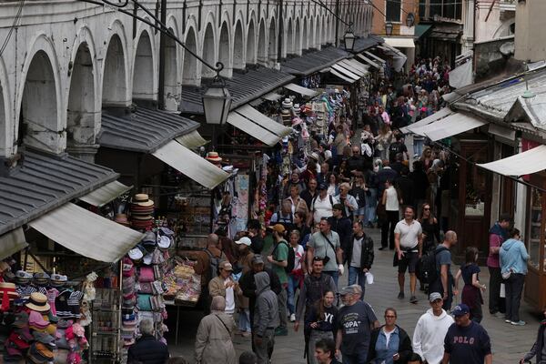 Tourists walk in Venice, Italy, Friday, April 18, 2025, Venice on Friday launches for a second year a pilot program to charge day-trippers an entrance fee. (AP Photo/Antonio Calanni)