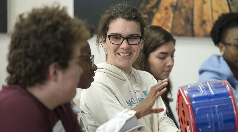 Mill Creek High School Junior Elise Page (center) passes her classmate optic fibers before a tour of the Heraeus manufacturing plant in Buford on Tuesday, Dec. 3, 2019. ALYSSA POINTER/ALYSSA.POINTER@AJC.COM