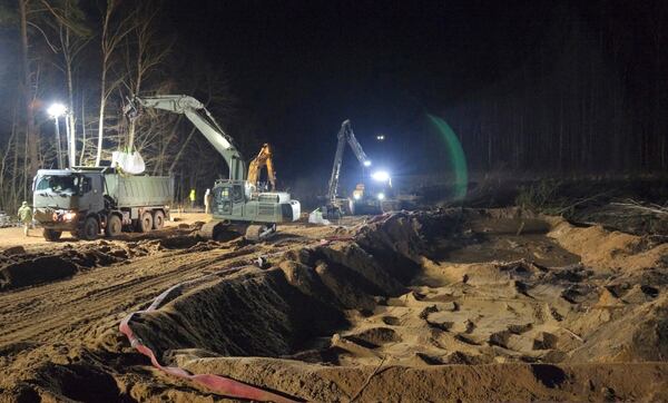 In this image provided by the U.S. Army, U.S. Army soldiers from the 1st Armored Brigade Combat Team, 3rd Infantry Division, along with Lithuanian Army and emergency services personnel, build a makeshift dam from HESCO barrier bags during recovery efforts for four U.S. soldiers in a U.S. Army M88 Hercules submerged under several meters of water in a swamp near a training area near Pabadre, Lithuania, Thursday, March 27, 2025. (Christopher Saunders/U.S. Army via AP)