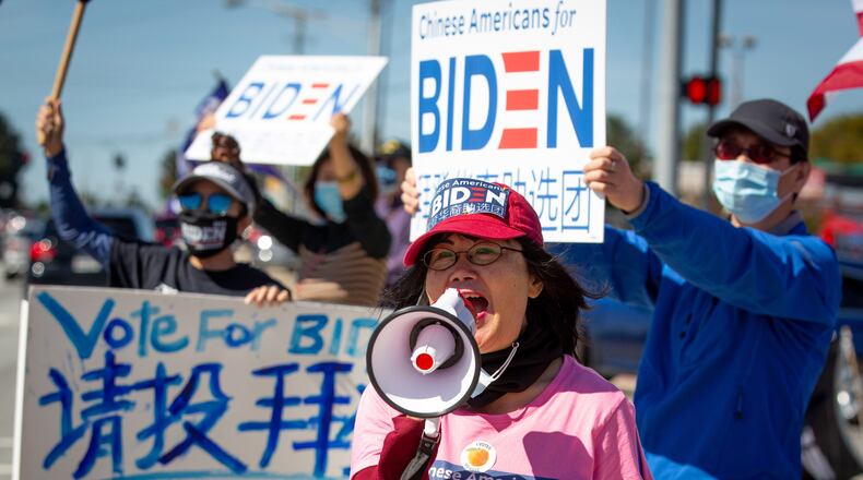 Asian Americans Democratic Club chairwoman Bilan Liao leads a groop in chants during a Chinese for Biden sign-waving rally along Pleasant Hill Rd Saturday, October 17, 2020. STEVE SCHAEFER / SPECIAL TO THE AJC
