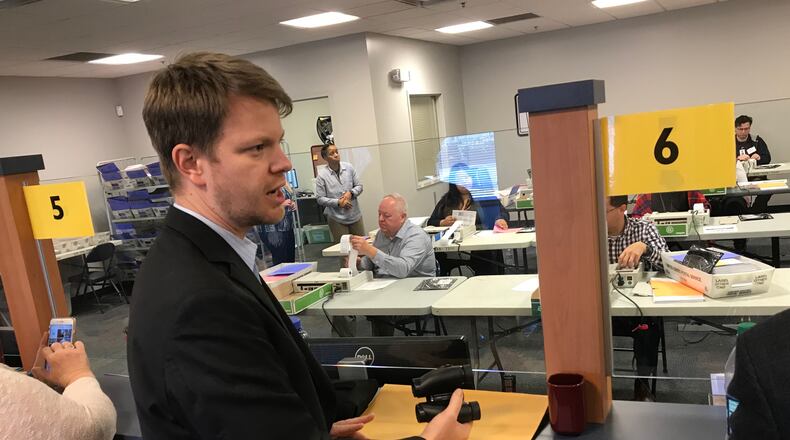 Spencer Smith, the campaign manager for Democratic candidate Carolyn Bourdeaux, holds binoculars Wednesday as the recount for the 7th Congressional District begins. Bourdeaux trails Republican incumbent Rob Woodall by just over 400 votes. TYLER ESTEP / TYLER.ESTEP@AJC.COM