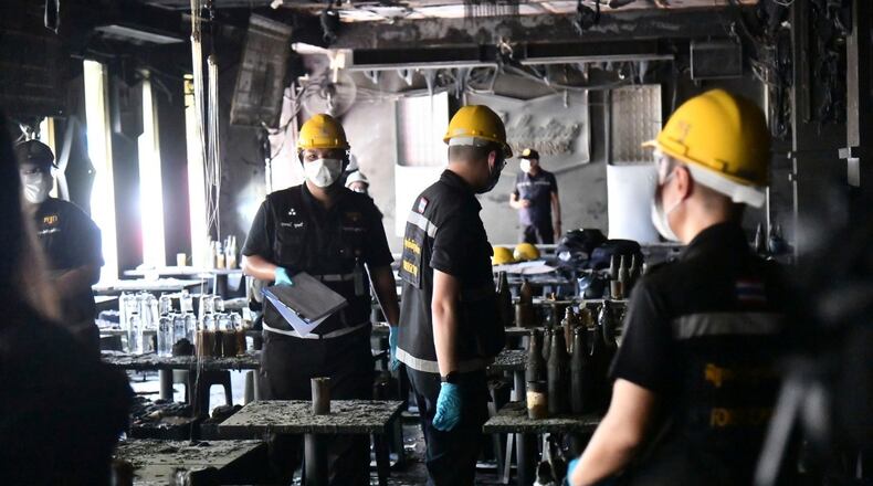 In this handout photo released by Bangkok Metropolitan Administration, forensic police officers inspect the site of a fire in Bangkok, Thailand, Monday, July 13, 2026. (Bangkok Metropolitan Administration via AP)