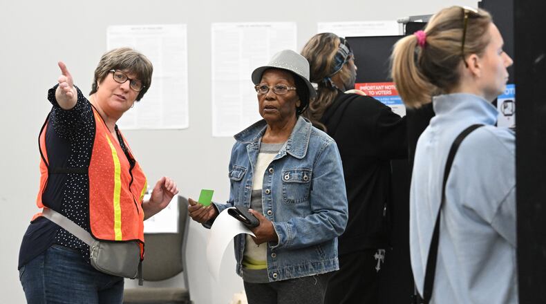 A poll worker helps voter Joyce Fraser (center) on Oct. 15 at the Cobb County Elections and Registration Office in Marietta. (Hyosub Shin/AJC)