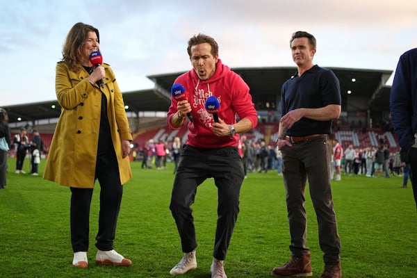 Wrexham co-owners Ryan Reynolds, center, and Rob McElhenney celebrate at the end of the English League One soccer match between Wrexham and Charlton Athletic at the Racecourse ground in Wrexham, Wales, Saturday, April 26, 2025. (AP Photo/Jon Super)