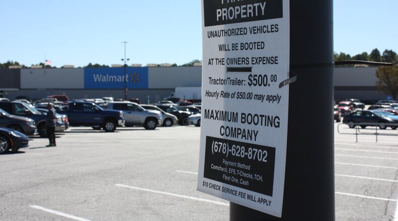 Signs in the Newnan Crossing shopping center in Newnan, Ga., warn owners of ‘unauthorized vehicles’ that they are subject to booting.