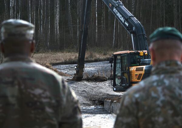 In this image provided by the U.S. Army, U.S. Army soldiers from the 1st Armored Brigade Combat Team, 3rd Infantry Division, along with Lithuanian Army and emergency services personnel, discuss their plan to recover four U.S. soldiers in a U.S. Army M88 Hercules submerged under several meters of water in a swamp near a training area near Pabadre, Lithuania, Thursday, March 27, 2025. (Christopher Saundersn/U.S. Army via AP)
