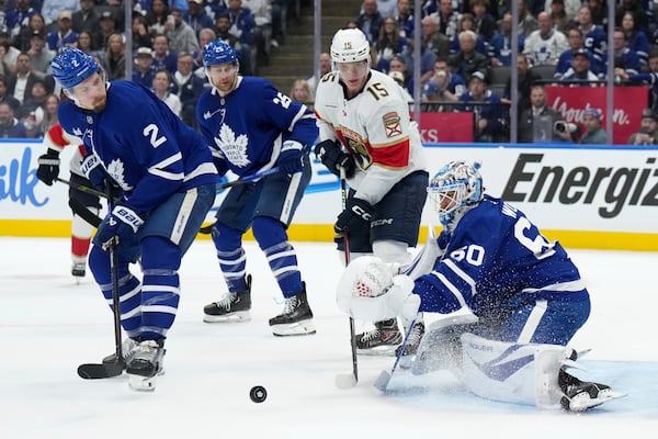 Toronto Maple Leafs goaltender Joseph Woll (60) makes a save while under pressure from Florida Panthers forward Anton Lundell (15) as Maple Leafs' Simon Benoit (2) and Brandon Carlo (25) watch during the third period of Game 1 in an NHL hockey second-round playoff series in Toronto, Monday, May 5, 2025. (Nathan Denette/The Canadian Press via AP)