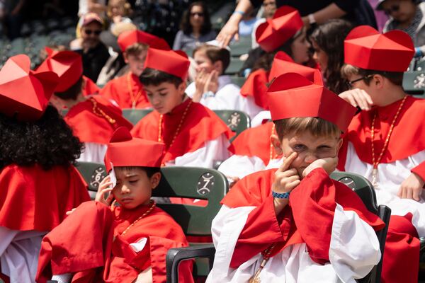 Students of Our Lady of Mt. Carmel Academy, who held a mock conclave before, wear cardinals' vestments during the Archdiocese of Chicago's celebration of Pope Leo XIV at Rate Field, Saturday, June 14, 2025. (Pat Nabong/Chicago Sun-Times via AP)