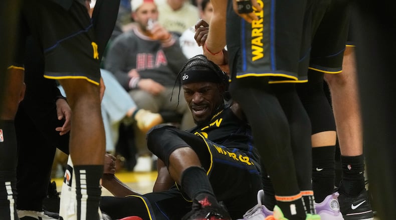 Golden State Warriors forward Jimmy Butler III, middle, is helped up by teammates during the second half of an NBA basketball game against the Miami Heat in San Francisco, Monday, Jan. 19, 2026. (AP Photo/Jeff Chiu)