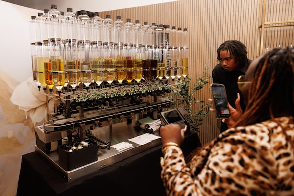 Attendees at a launch event for Indiehouse Modern Fragrances watch the custom perfume-making process happen on the AI-enabled machine. (Estela Muñoz/AJC)