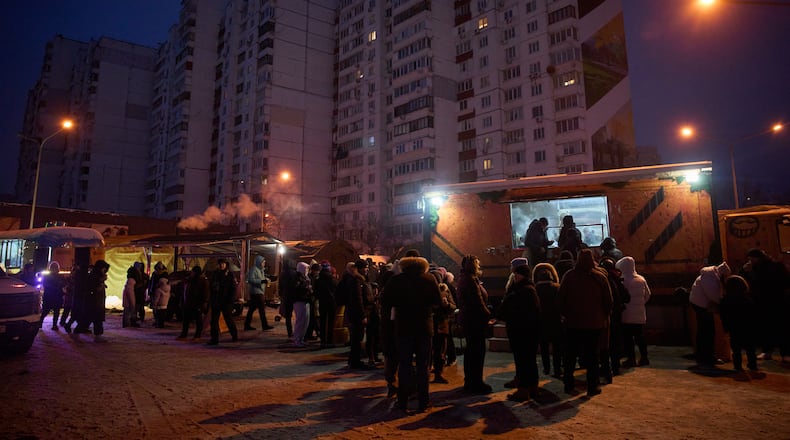 People stand in line for free hot meals that veterans of the 3rd Separate Assault Brigade of Ukraine's Armed Forces serve in residential neighborhood as repeated Russian air attacks on the country's energy sector leave people without power, heating and water in the harshest winter in decades in Kyiv, Ukraine, Sunday, Feb. 8, 2026. (AP Photo/Efrem Lukatsky)