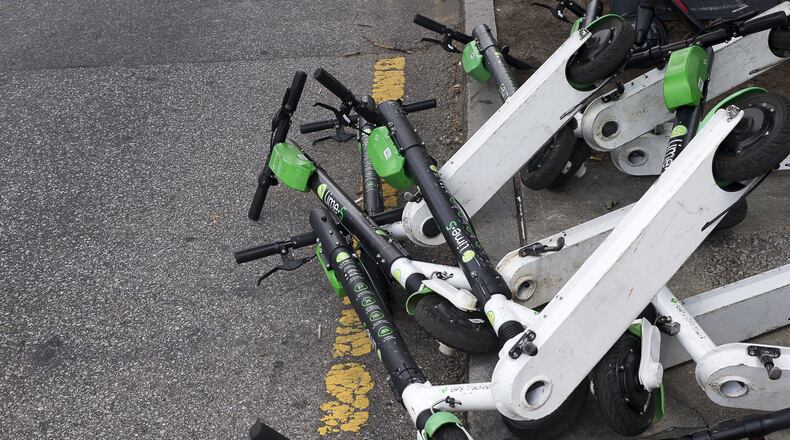 Sharable e-scooters lay knocked in a lane along Centennial Olympics Park Drive NW near Centennial Olympic Park Atlanta. (Alyssa Pointer/alyssa.pointer@ajc.com)