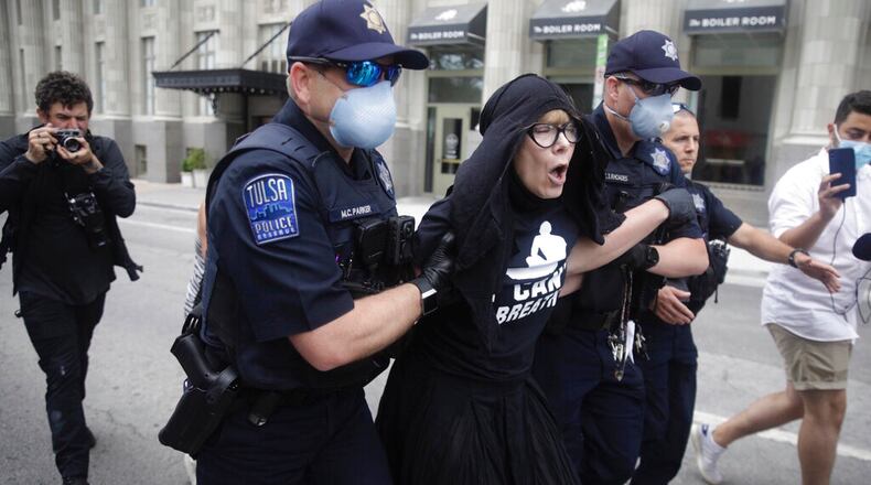 Tulsa Police officers arrest protester for trespassing after she entered the safety barricade of President Donald Trump's campaign rally Saturday June 20, 2020. (Mike Simons/Tulsa World via AP)