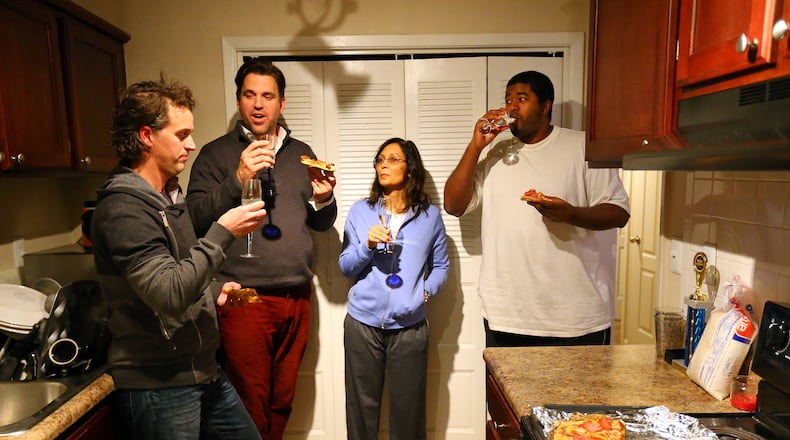 Daniel Ringenberg (from left), Conn Jackson, Rebecca Ganguly and Etienne Bertie share a meal of pizza and sparkling water in Jackson's kitchen on Wednesday night, Jan. 29, 2014. Jackson took 10 strangers into his Vinings apartment during the snowstorm and kept three of them a second day.
