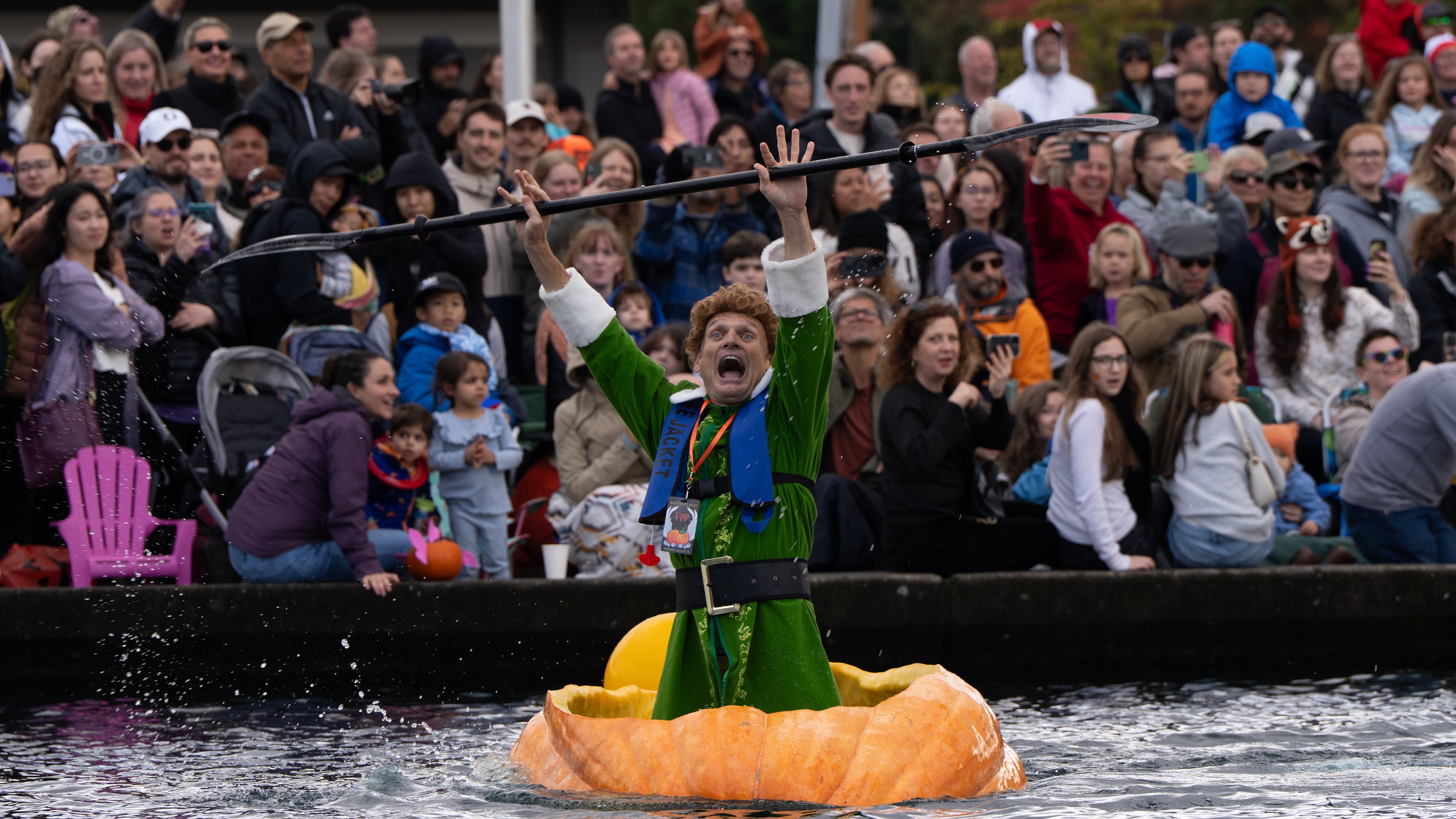 Gary Kristensen, dressed up as the character Buddy from the holiday movie "Elf," celebrates after winning a race during the West Coast Giant Pumpkin Regatta on Sunday, Oct. 19, 2025, in Tualatin, Ore. (AP Photo/Jenny Kane)