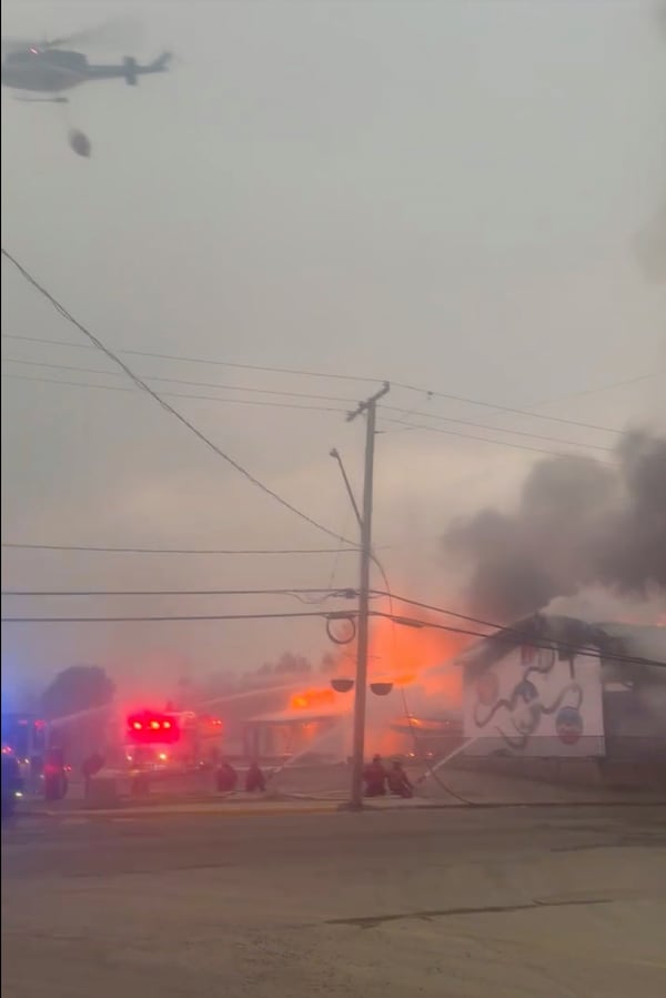 In this photo provided by Evan Bell firefighters combat the wildfires as they consumed Robertson Trading, a general store, in La Ronge, Saskatchewan on June 3, 2025. (Evan Bell via AP)