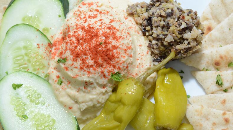 Hummus and Olive Tapenade are served as one appetizer - both on a plate with pita wedges and vegetables — at Front Page News.