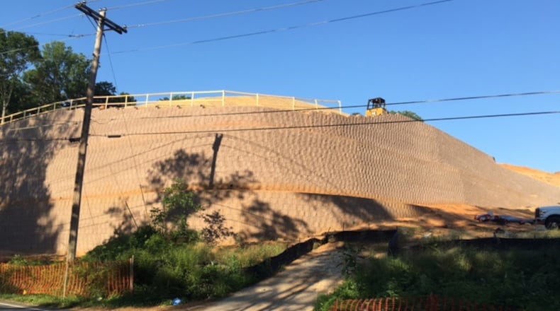 The retaining wall along Coleman Road, seen in this AJC file photo, has been dubbed "The Great Wall of Roswell". Recent video shows water spilling over the wall flooding the areas below.
