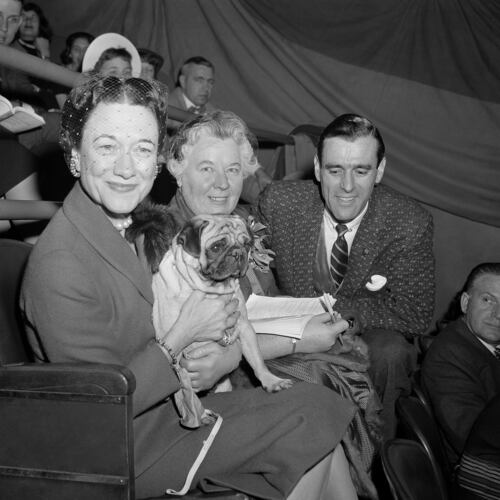 FILE - The Duchess of Windsor, Wallis Simpson, left, holds Ch. Pugville's Golden Victory during judging of the pug class during the Westminster Kennel Club Show at Madison Square Garden in New York, Feb. 13, 1956, as the dog's owner, Arnold Canton, far right, and dog breeder Harriet Smith, look on. (AP Photo/Jacob Harris, File)