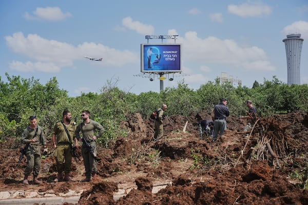 Israeli security forces inspect the site where the Israeli military said a projectile fired by Yemen's Houthi rebels landed in the area of Ben Gurion International Airport near Tel Aviv, Israel, on Sunday, May 4, 2025. (AP Photo/Ohad Zwigenberg)