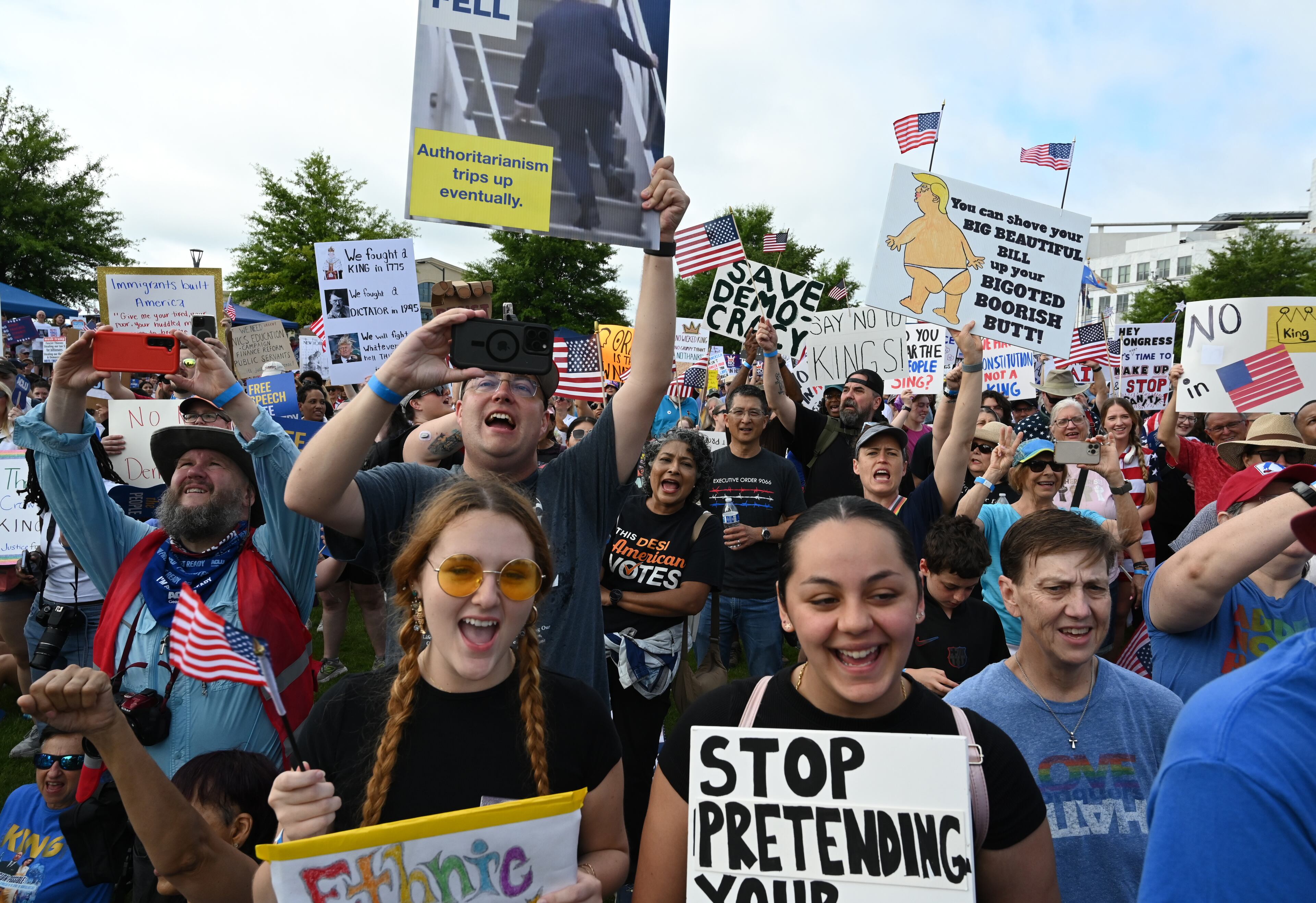Demonstrators hold signs at Liberty Plaza, near the Georgia Capitol, for a "No Kings" protest to oppose Trump’s immigration policies, Saturday, June 14, 2025, in Atlanta. (Hyosub Shin / AJC)
