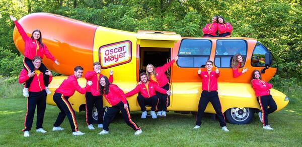 Out of more than 7,000 applicants for the 2024-25 season, Oscar Mayer selected these 12 Wienermobile drivers, including Columbus native Sarah Oney (the person on the right in the “bun roof”). They are posing in Madison, Wisconsin, where the drivers trained for two weeks in June 2024. (Photo provided by Sarah Oney)