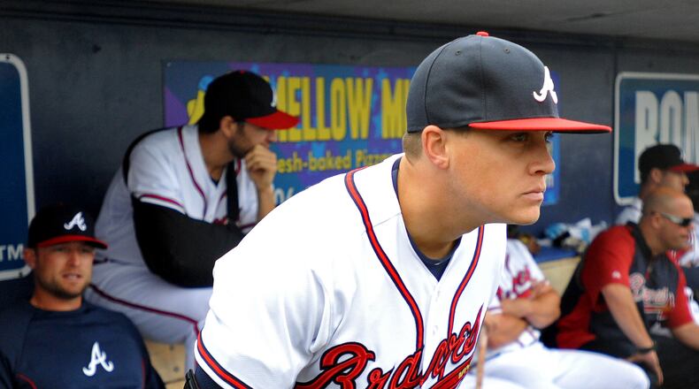 Atlanta Braves pitcher Kris Medlen wears an elbow brace on his right arm after season-ending Tommy John surgery as he waits during a rain delay in their exhibition baseball game against the team's minor league Future Stars Saturday, March 29, 2014, in Rome, Ga. (AP Photo/David Tulis)