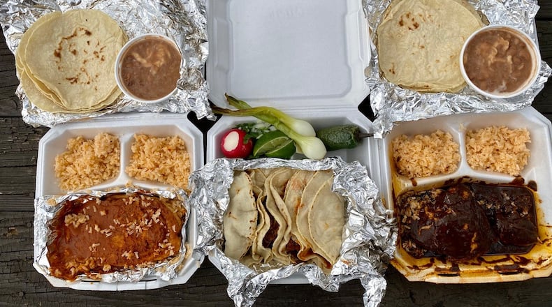This feast of takeout dishes from Taqueria La Oaxaquena in Jonesboro includes: chile rellenos; a plate of four tacos; and chicken mole. Wendell Brock for The Atlanta Journal-Constitution