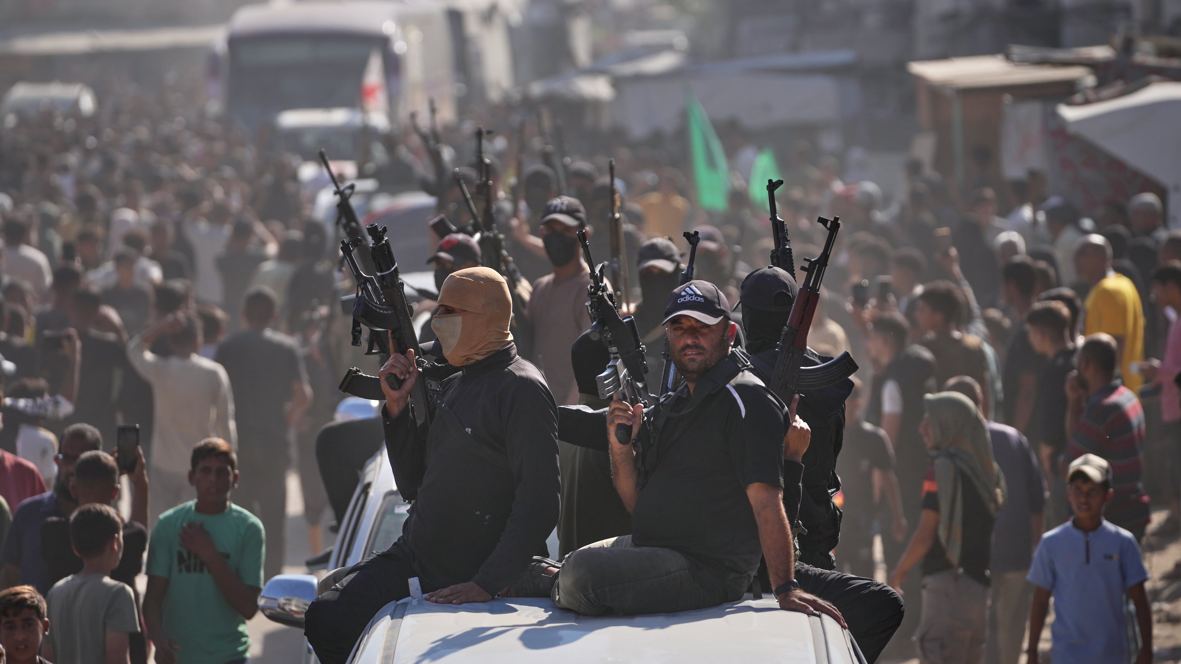 Hamas gunmen on pickup trucks escort buses carrying freed Palestinian prisoners as they are greeted following their release from Israeli jails under a cease-fire agreement between Hamas and Israel, in Khan Younis, southern Gaza Strip, Monday, Oct. 13, 2025. (AP Photo/Jehad Alshrafi)