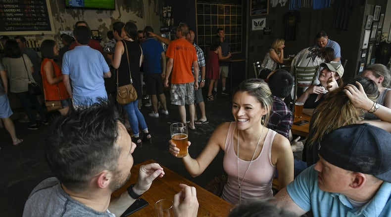 Emily Handziuk of Atlanta (second from right) holds a beer while talking to friends Ashton Pierre (left) and Jonathan Peardon (right), also from Atlanta, at Gate City Brewing recently. CONTRIBUTED BY JOHN AMIS