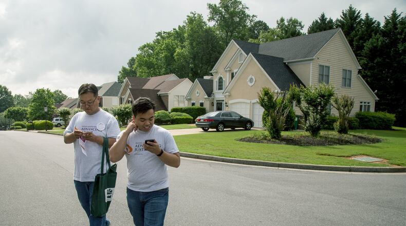 Volunteer Jongwon Lee, left, and Asian Americans Advancing Justice program associate Raymond Partolan walk Saturday through a Johns Creek neighborhood talking with residents about the 6th Congressional District’s new May 21 voter registration deadline. STEVE SCHAEFER / SPECIAL TO THE AJC