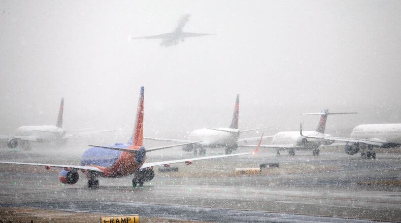 Planes line up on the tarmac as snow falls delaying travel at Hartsfield-Jackson Atlanta International Airport Friday, Dec. 8, 2017, in Atlanta. (Bob Andres/Atlanta Journal-Constitution via AP)