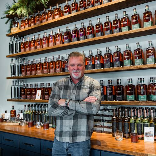 Jeff Arnett stands among bottles of Company Distilling whiskey, the brand he helped build as part of his second act in the spirits industry. (Courtesy of Leonard Garrison)