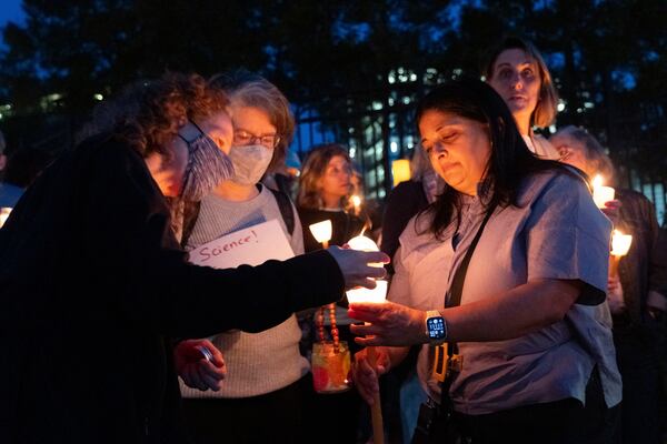 People including Sasha Patel, right, who retired after working 25 years at the Centers for Disease Control and Prevention, gather for a candlelight vigil in front of its headquarters in Atlanta, Friday, March 28, 2025. (AP Photo/Ben Gray)