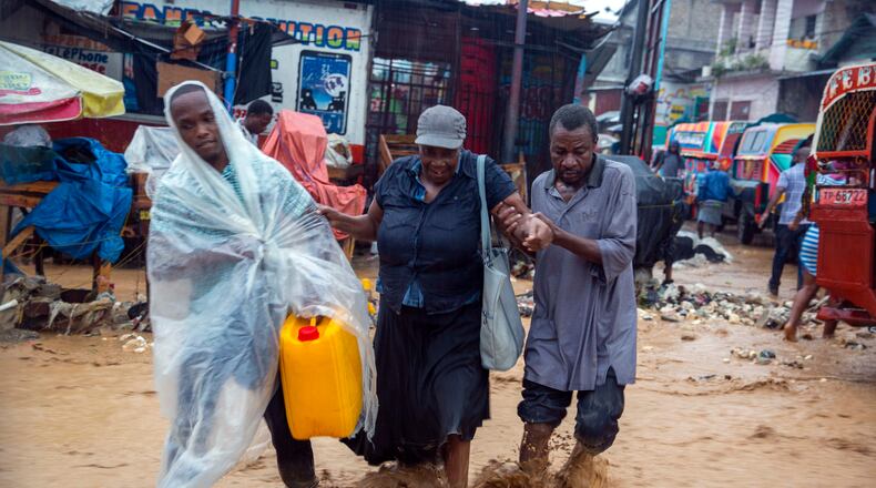Street vendors wade a flooded street during the passing of Tropical Storm Laura in Port-au-Prince, Haiti, on Sunday. Laura battered the Dominican Republic and Haiti and is heading for a possible hit on the Louisiana coast at or close to hurricane force, along with Tropical Storm Marco.