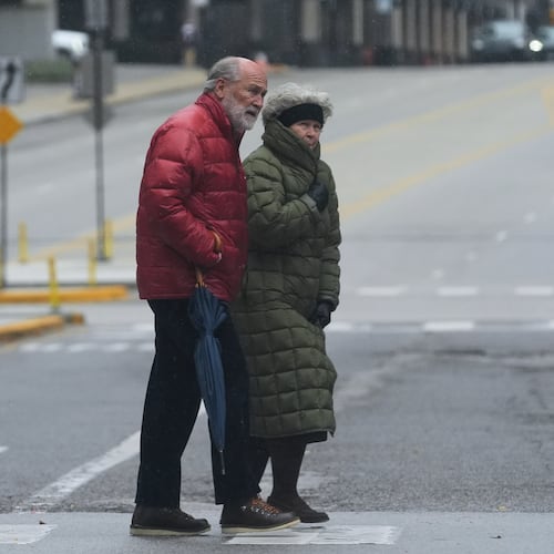 Pedestrians cross a street during a cold day in Chicago, Sunday, Nov. 9, 2025. (AP Photo/Nam Y. Huh)