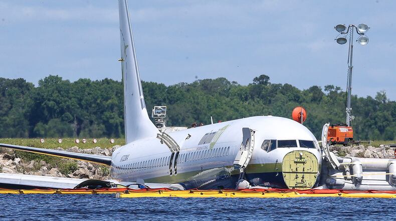 A charter plane carrying 143 people and traveling from Cuba to north Florida sits in a river at the end of a runway, Saturday, May 4, 2019 in Jacksonville, Fla.  The Boeing 737 arriving at Naval Air Station Jacksonville from Naval Station Guantanamo Bay, Cuba, with 136 passengers and seven aircrew slid off the runway Friday night into the St. Johns River, a NAS Jacksonville news release said. (AP Photo/Gary McCullough)