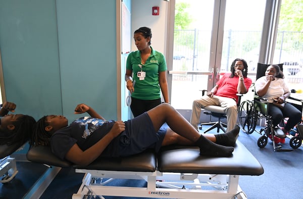 Physical therapist Anzika Tuliva (standing) talks to Preston Veal as his parents, Bernice and Damien Veal, ask questions about Preston's recovery. (Hyosub Shin/AJC)