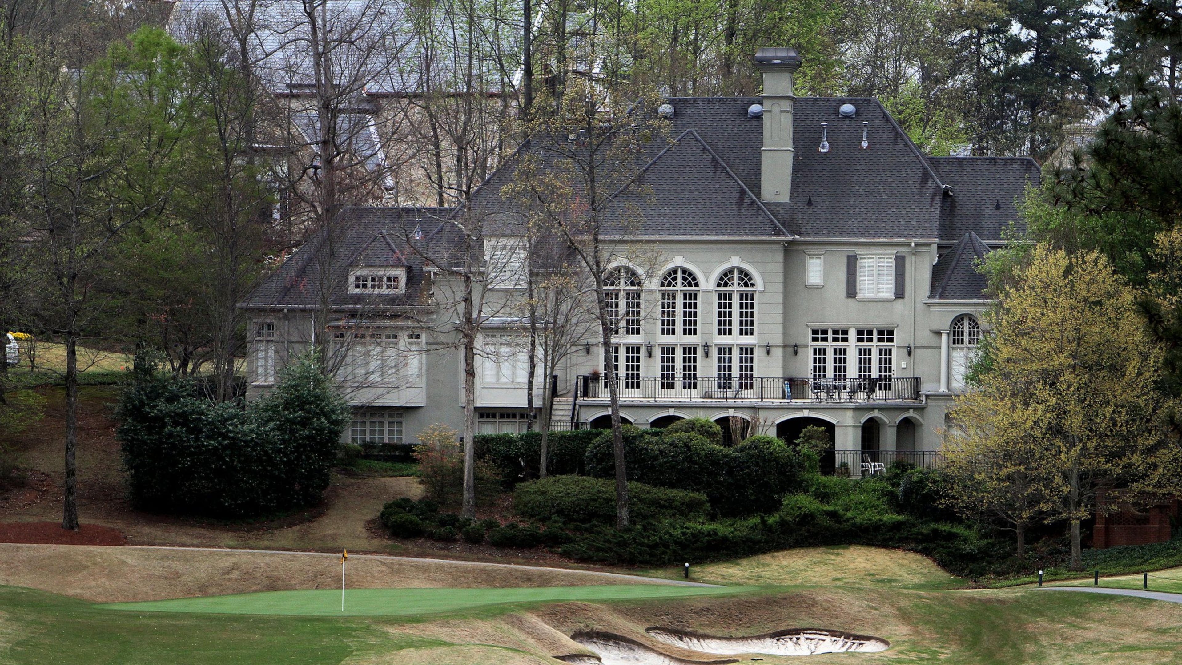 A huge home sits next to a green on the golf course at the Country Club of the South in Johns Creek. (AJC File)
