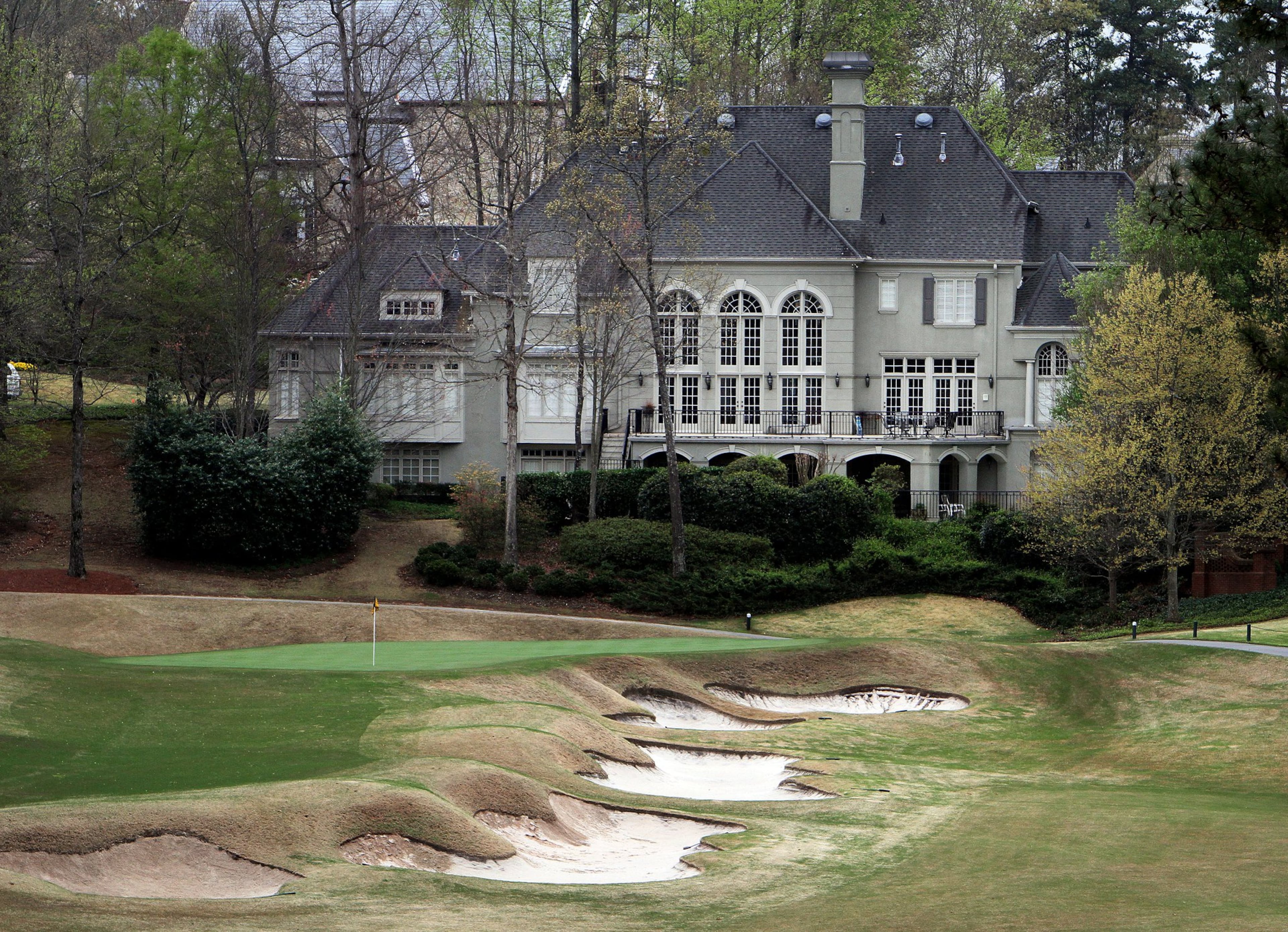 A huge home sits next to a green on the golf course at the Country Club of the South in Johns Creek. (AJC File)