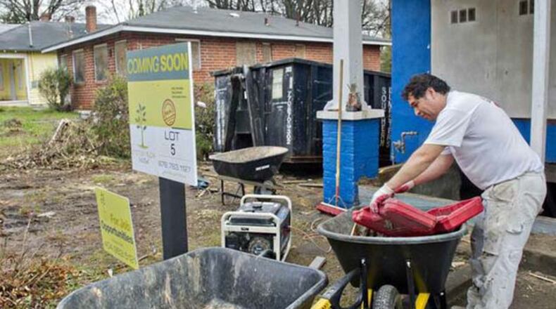 Jose Garcia looks for a tool as he works to rehab the space that used to be the front porch of the house on Beryl Street in the Pittsburgh community. The house is one of 53 properties that have been bought by a group trying to revive one of Atlanta's oldest neighborhoods.